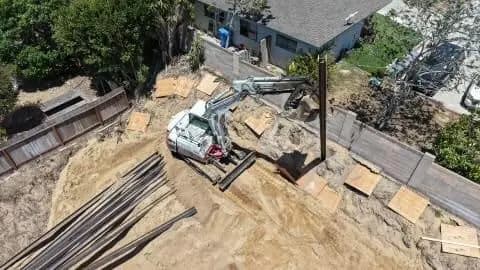 Aerial view of steel I-beams staged beside the excavation area in Redondo Beach
