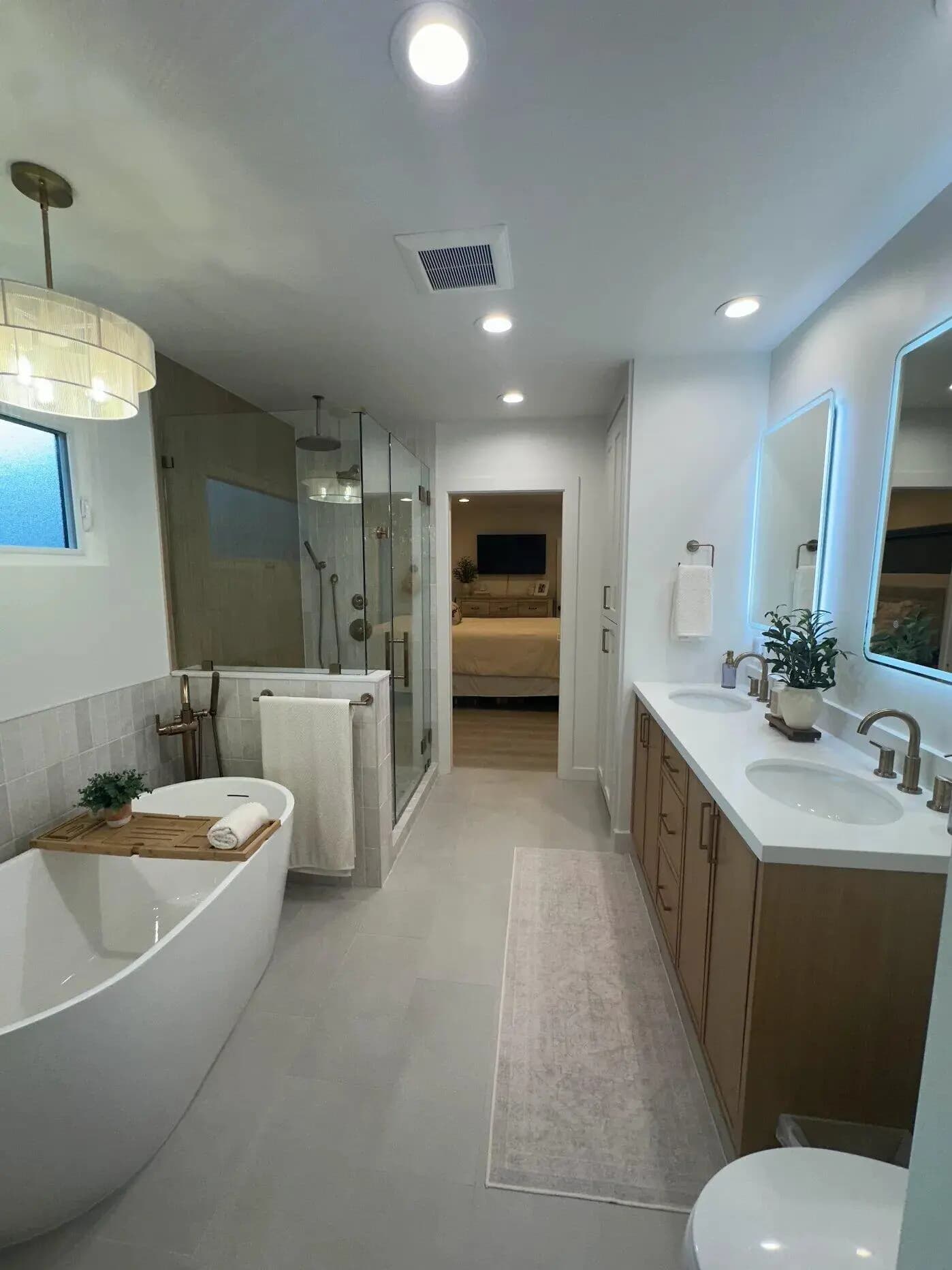 Double vanity with backlit mirrors and brushed brass fixtures in custom master bathroom Long Beach