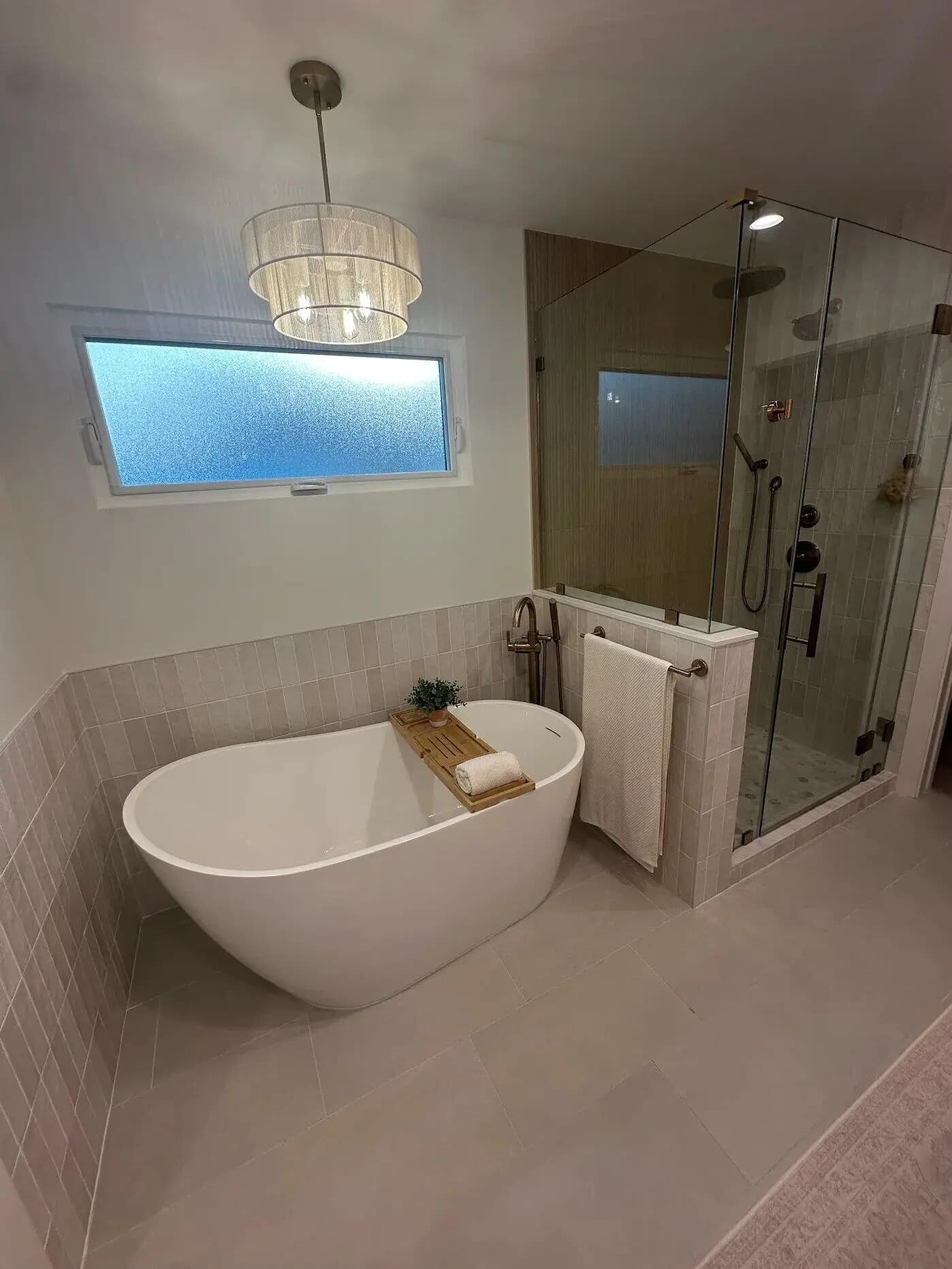 Freestanding bathtub and frameless glass shower with neutral tile in master bathroom addition Long Beach