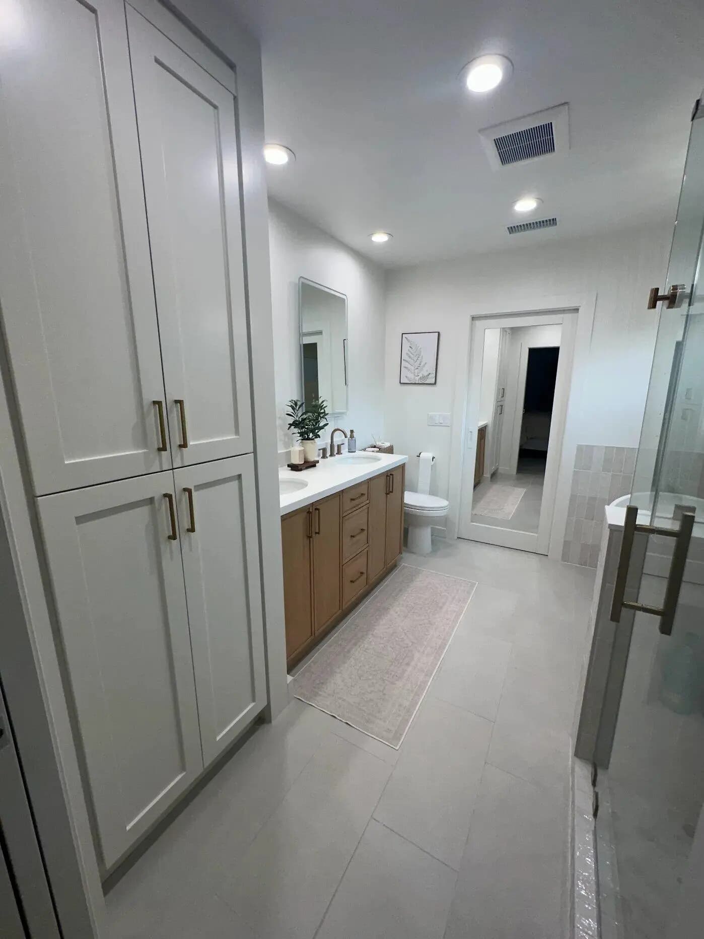 Walk-in shower with frameless glass enclosure and rainfall showerhead in Long Beach master bathroom addition