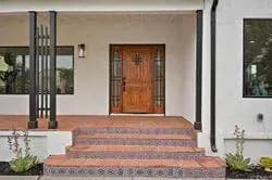 Spanish-style front entry with custom wood door and tile steps