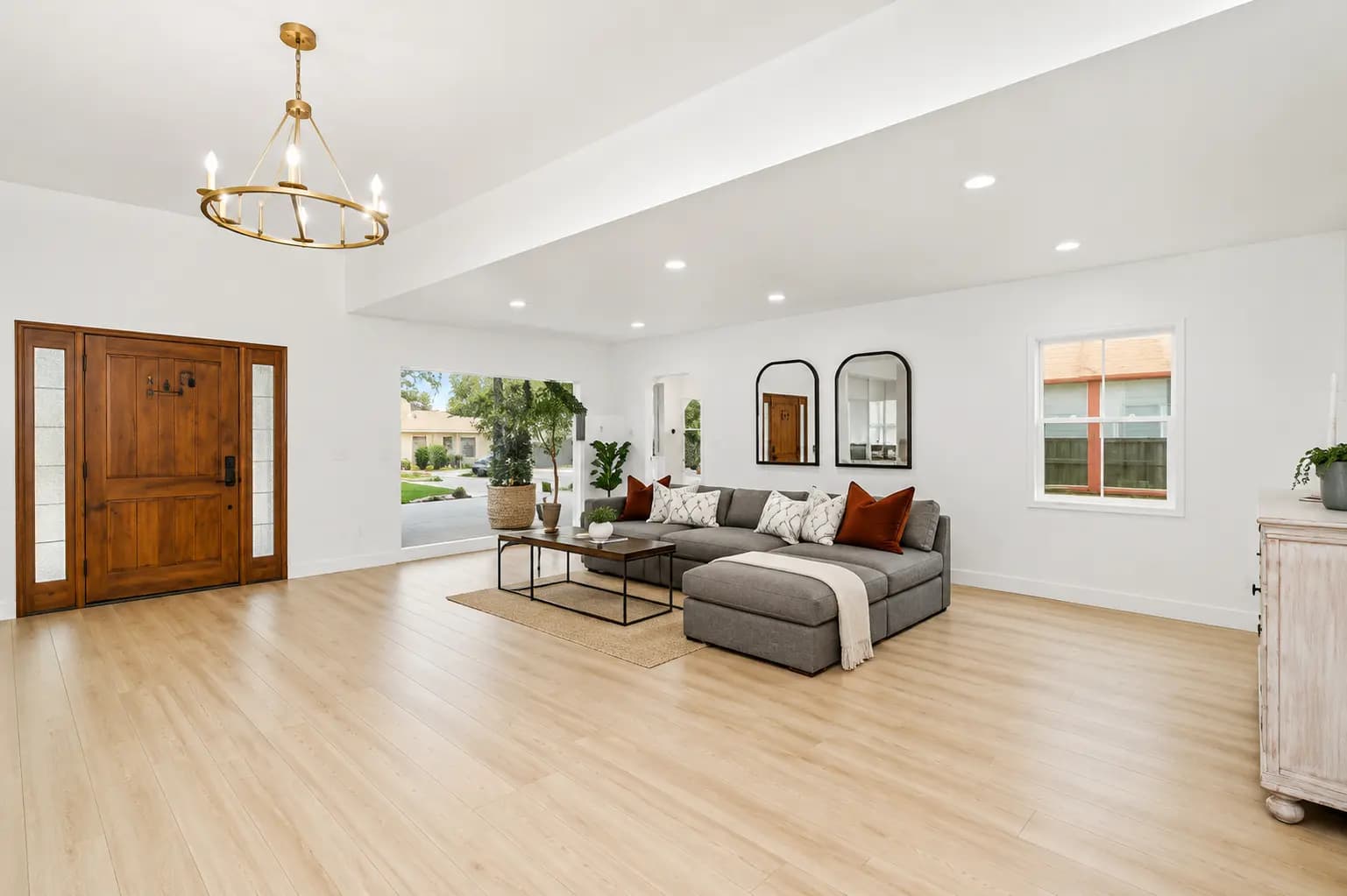 Open-concept luxury interior with custom entry door, brass chandelier, and European oak flooring