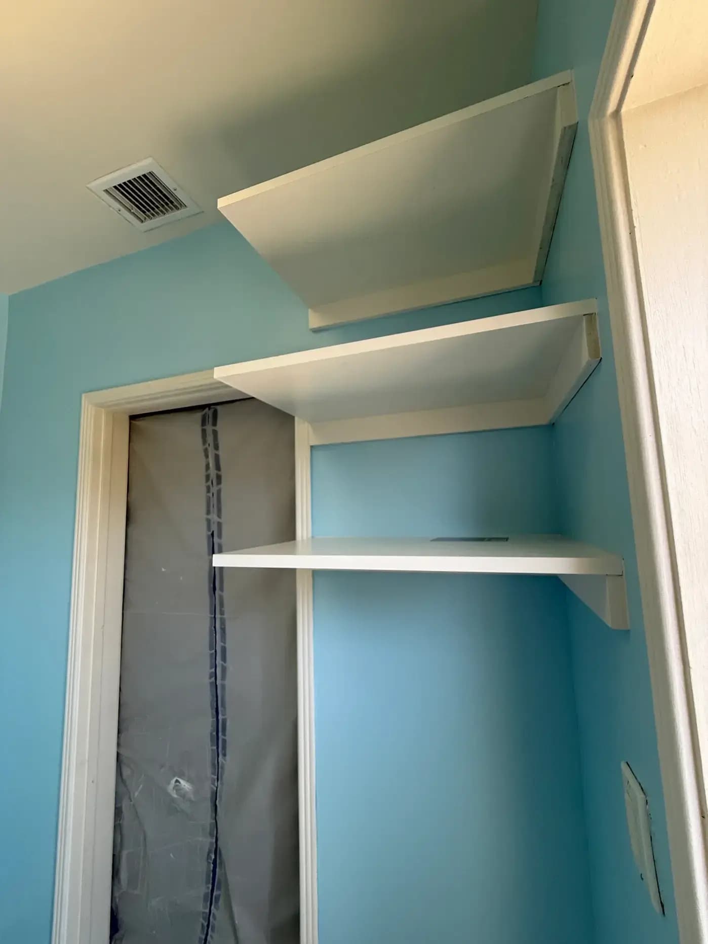 Finished laundry room corner with blue walls and white shelving