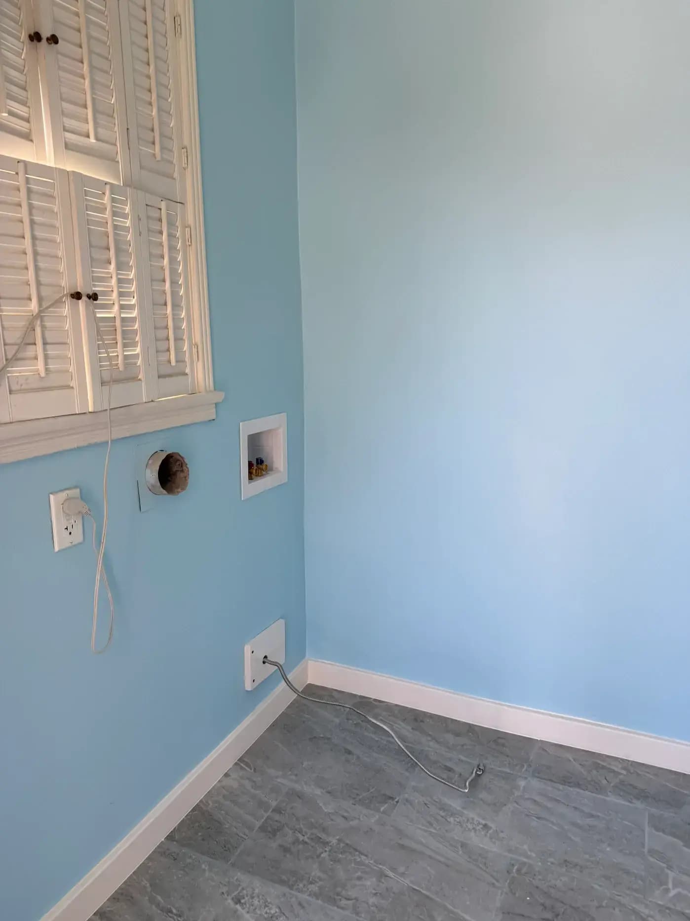 Finished laundry room corner with plantation shutters, washer and dryer hookups, and new baseboards