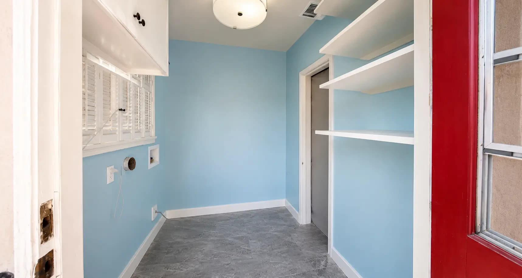 Renovated Long Beach laundry room with sky blue walls, white cabinetry, grey tile floors, and washer-dryer hookups