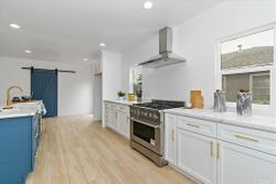 Custom kitchen with stainless range hood and barn door pantry