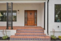 Spanish-style front entry with custom wood door and tile steps