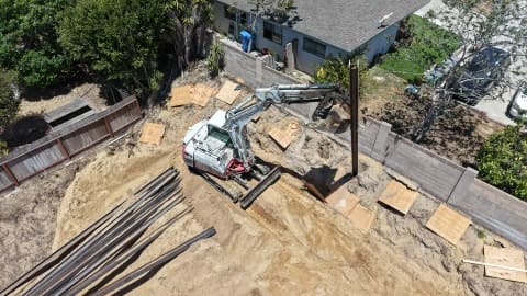 Aerial view of steel I-beams staged beside the excavation area in Redondo Beach